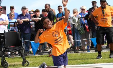 Boy winding up to throw shotput in front of a crowd