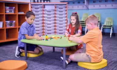 Children sitting at a low table stacking blocks