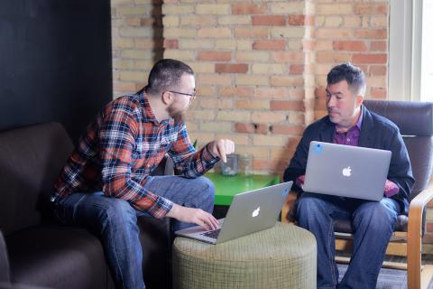 Ben points to his laptop screen while coworker looks on