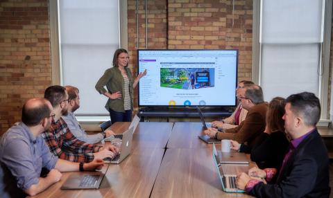 RDG team member presents screen to meeting table full of coworkers