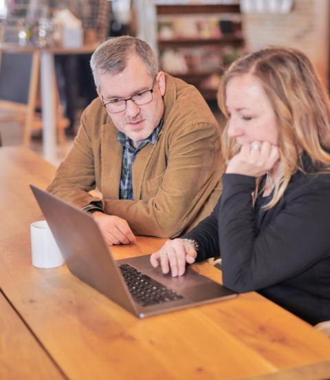 Two people talking while looking at a laptop screen