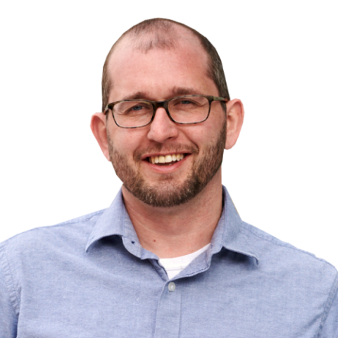 Joe Maag head and shoulders, with glasses, stubble, and light blue dress shirt