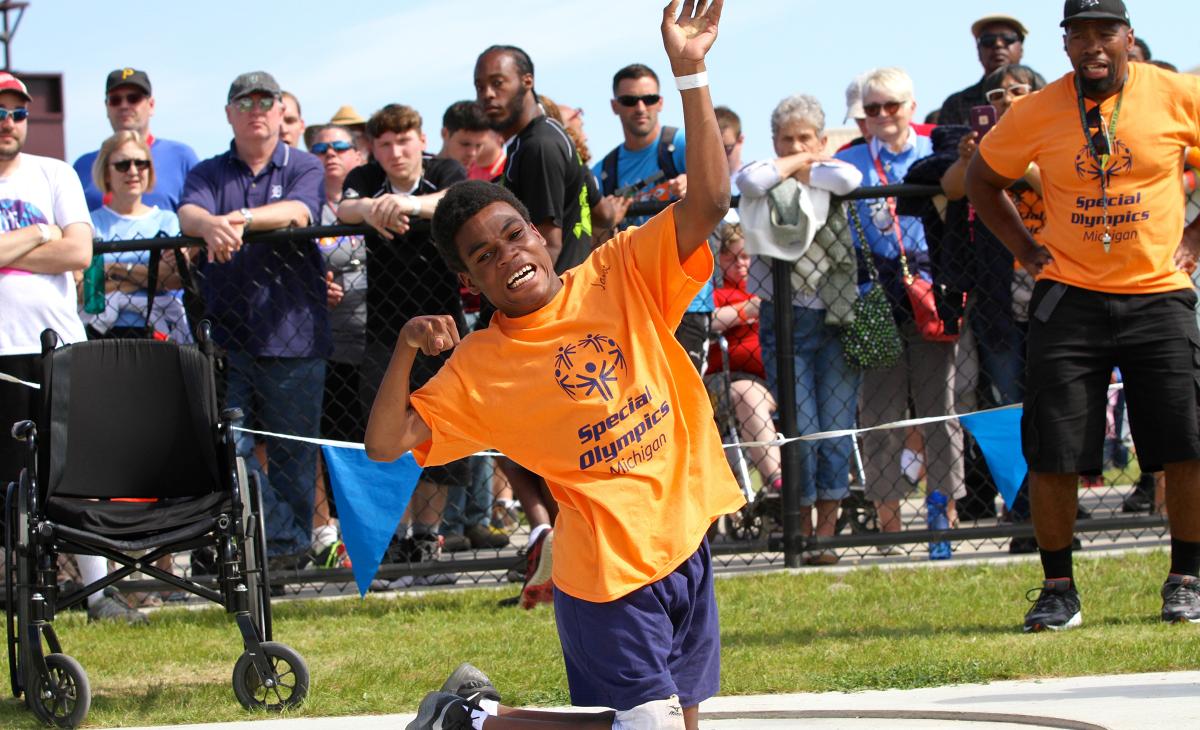Boy winding up to throw shotput in front of a crowd