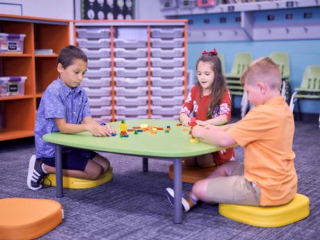 Children sitting at a low table stacking blocks