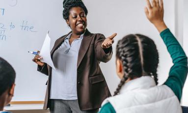 Teacher pointing to a student whose hand is raised.